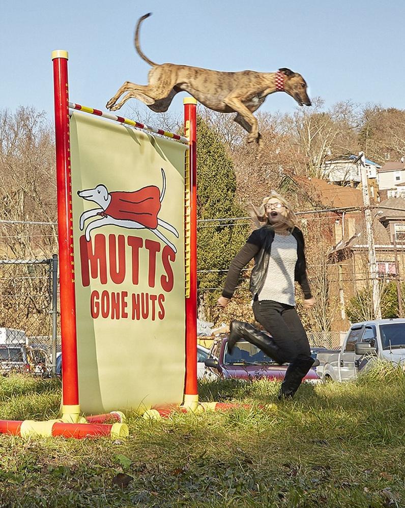 Feather, a greyhound rescue, jumps over a hurdle as owner Samantha Valle cheers her on in this undated photo.