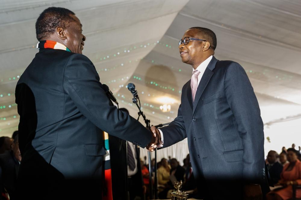 Zimbabwe President Emmerson Mnangagwa (L) shakes hands with Finance and Economic Development Minister, Professor Mthuli Ncube, during the swearing in ceremony for Zimbabwe's new cabinet ministers at State House, Harare, on September 10, 2018.  —  AFP