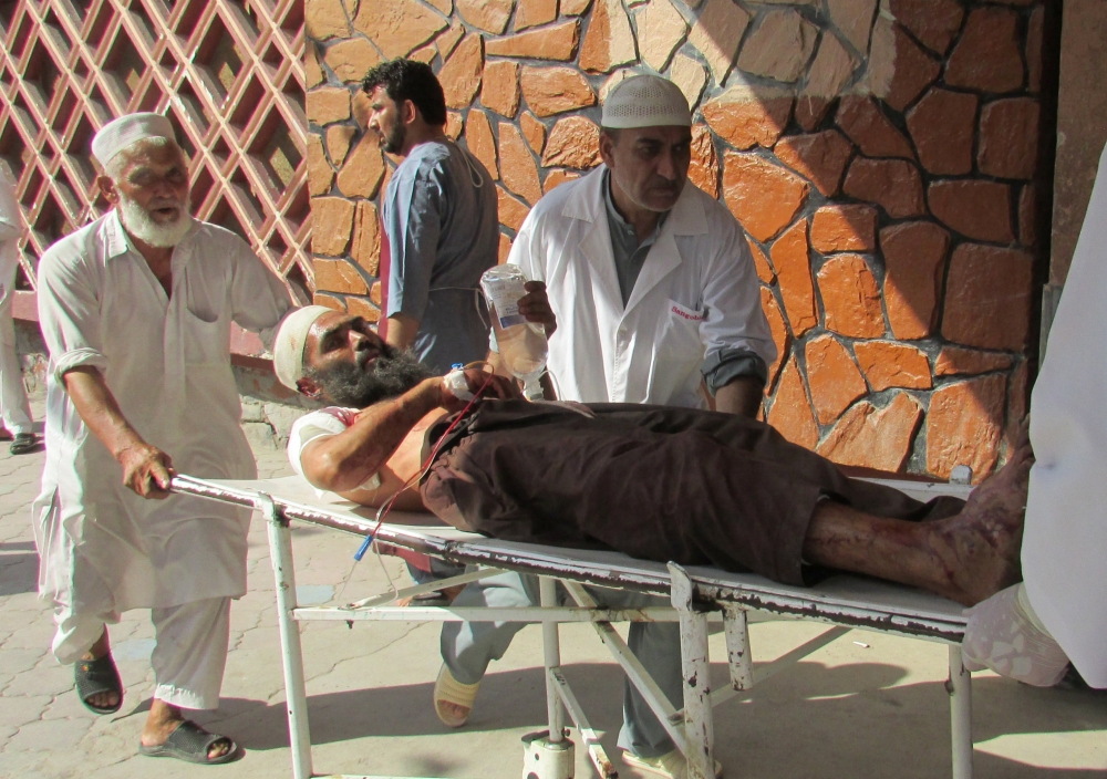 Afghan men carry an injured man to a hospital after a suicide attack in Nangarhar province, Afghanistan, on Tuesday. — Reuters