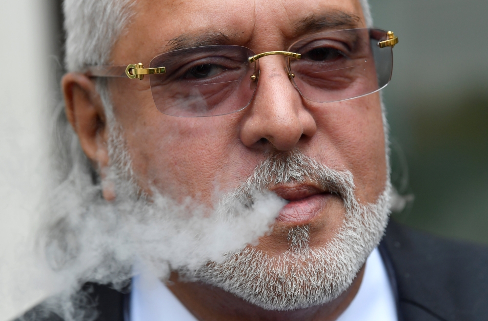 Vijay Mallya smokes outside Westminster Magistrates Court in London on Wednesday. — Reuters