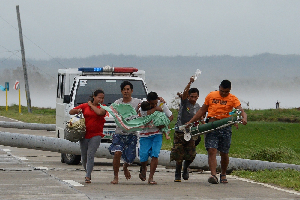 A father carries his sick child as its being transferred to another car as their ambulance is struck on a highway by toppled electric posts caused by strong winds after Typhoon Mangkhut hit Baggao town in Cagayan province, north of Manila, Saturday. — AFP