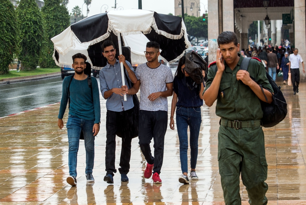 Moroccan youth are pictured walking in a street in the capital Rabat. — AFP