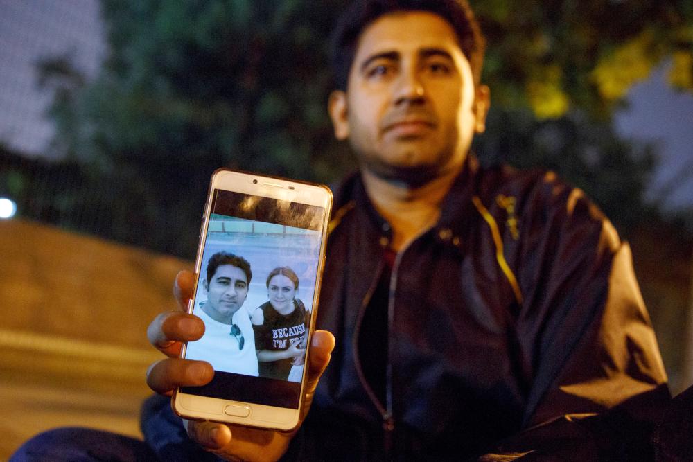 


Pakistani businessman Mirza Imran Baig shows a picture of him and his wife Mailikemu Maimati as he sits outside the Pakistani embassy in Beijing, China, on Tuesday. — Reuters