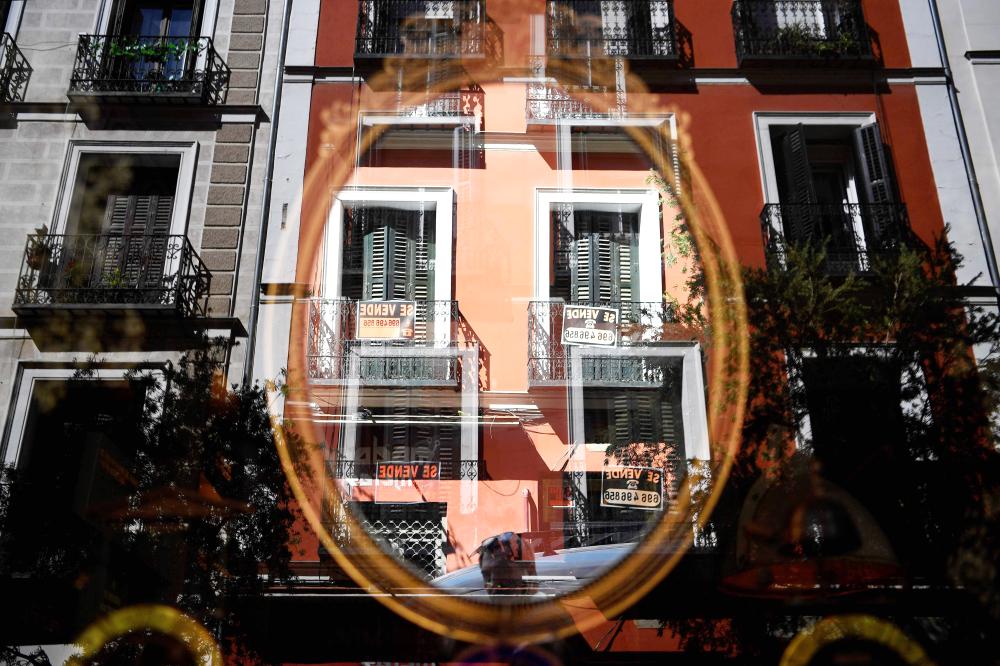 


This picture taken on Tuesday shows signs reading “For sale” hanging from balcony and reflected on a mirror in a shop in Madrid. — AFP