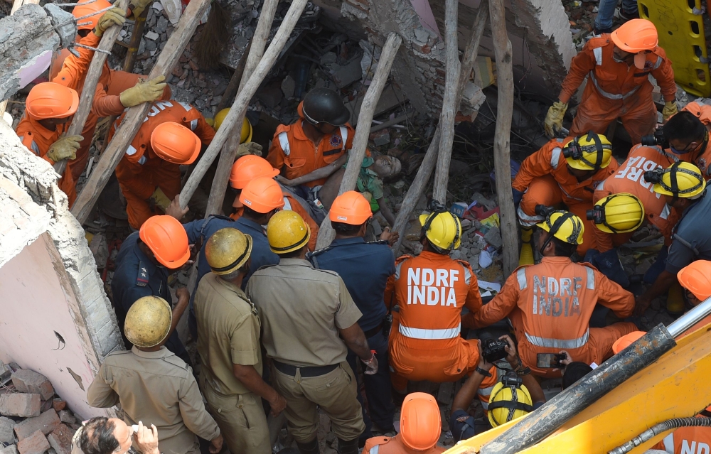 Members of the National Disaster Response Force (NDRF) remove the body of a young boy from the debris after a residential building collapsed in New Delhi on Wednesday. — AFP