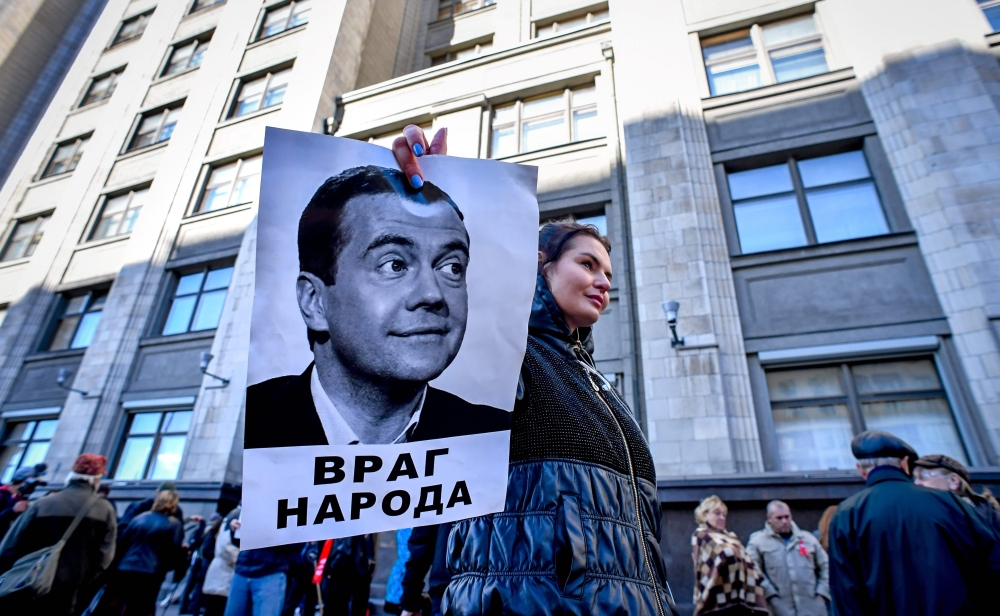 A protester holds a picture of Russian Prime Minister Dmitry Medvedev bearing an inscription reading “An enemy of people” during a rally against the pension reform in front of the State Duma, the lower house of parliament, in Moscow on Wednesday. — AFP