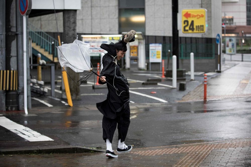 A man struggles to hold his umbrella as he walks against the strong wind after Typhoon Trami hit the city of Kagoshima on Kyushu island, Sunday. — AFP