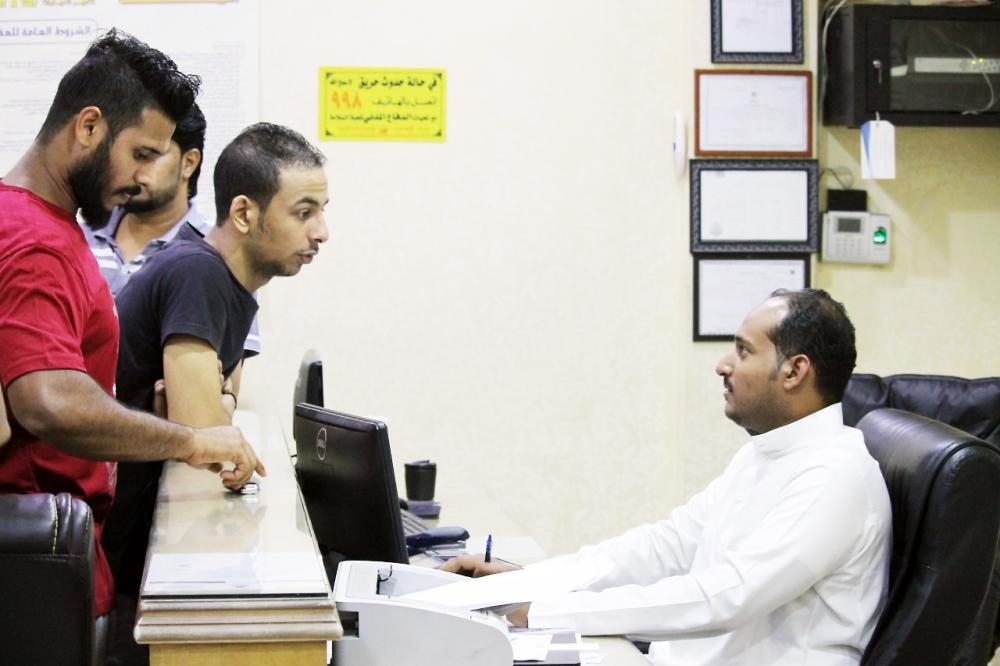 


A Saudi employee serves customers at a car rental office.