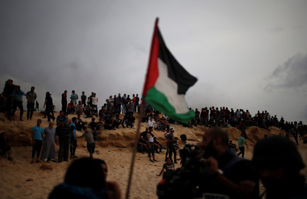 Palestinians gather during a protest calling for lifting the Israeli blockade on Gaza, on a beach near the maritime border with Israel, in the northern Gaza Strip, Monday. — Reuters