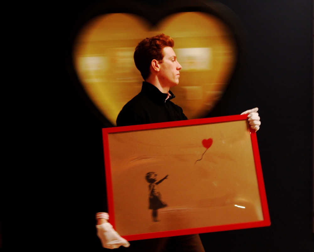 


An employee walks with Banksy’s “Girl and Balloon” 2009,  at Bonhams auction house in London on March 23, 2012. — Reuters