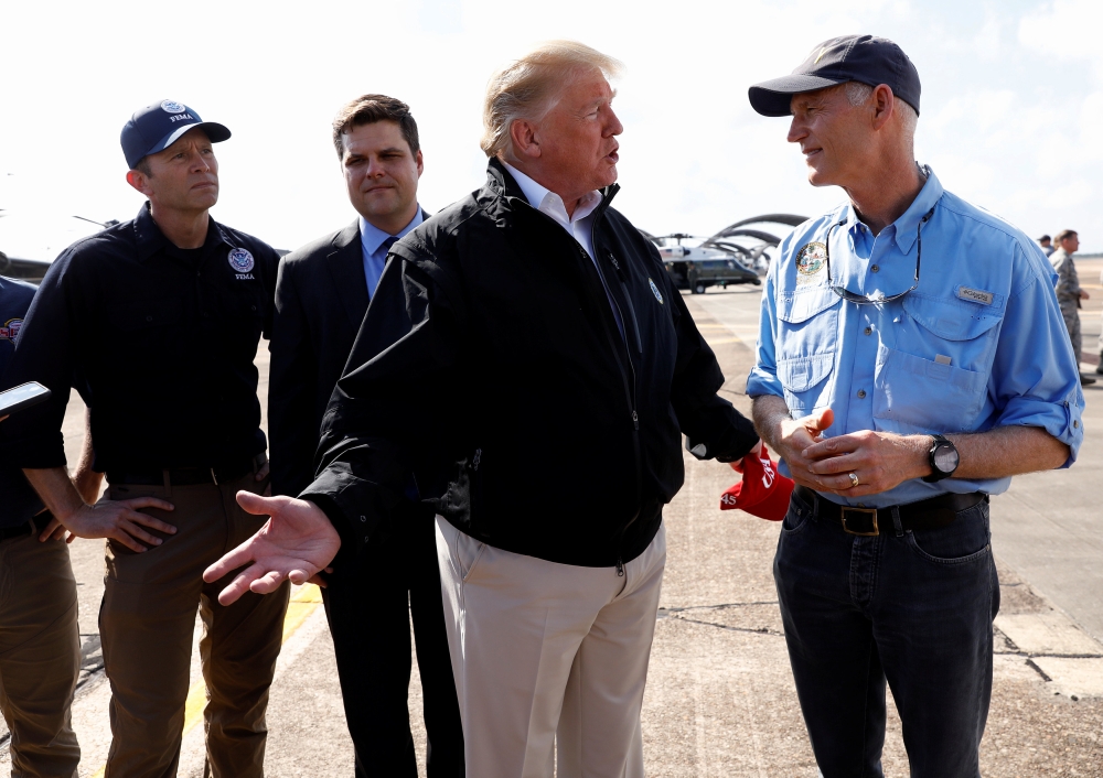 US President Donald Trump stands with FEMA Administrator Brock Long, left, and US Rep Ron DeSantis  as he talks to Florida Governor Rick Scott, right, after the president arrived to tour storm damage from Hurricane Michael at Eglin Air Force Base, Florida, on Monday. — Reuters