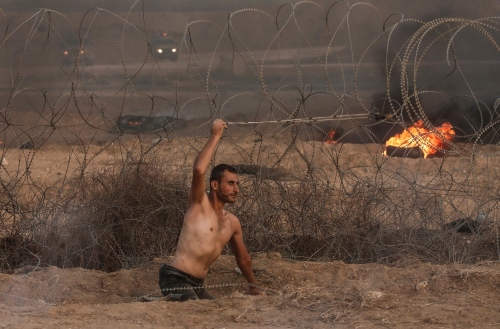 Disabled Palestinian Saber Al Ashqar, aged 29, uses a slingshot to throw stones at Israeli forces during a demonstration near the border with Israel, east of Gaza City, on Friday. — AFP