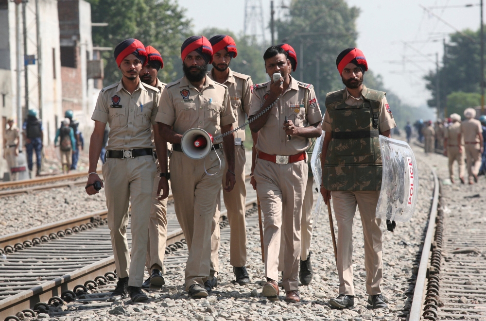 A policeman on Sunday speaks over a megaphone asking people to stay away from the railway track after a commuter train travelling at high speed ran over a crowd in Amritsar, India, on Friday. — Reuters