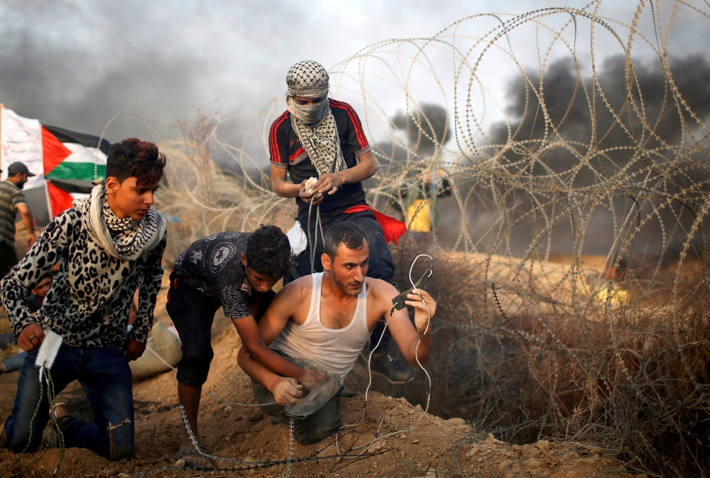 


A disabled Palestinian is helped as he uses a sling to hurl stones at Israeli troops during a protest calling for lifting the Israeli blockade on Gaza and demanding the right to return to their homeland, at the Israel-Gaza border fence in Gaza. — Reuters