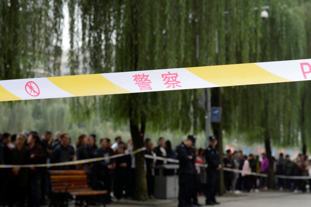 Police officers are seen behind a cordon near the gate of a kindergarten where a woman armed with a kitchen knife attacked children in Chongqing, China, on Friday. — Reuters