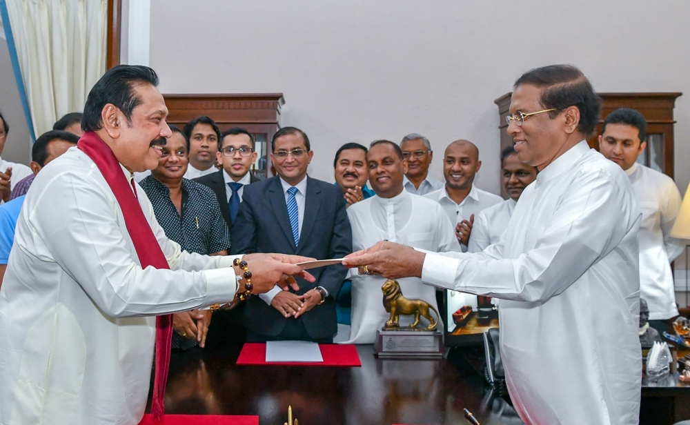 This handout released by Sri Lanka President media on Friday shows former Sri Lankan president Mahinda Rajapakse (L) handing over documents to Sri Lankan President Maithripala Sirisena (R) as Rajapakse is sworn in as new Prime Minister, in Colombo. — AFP