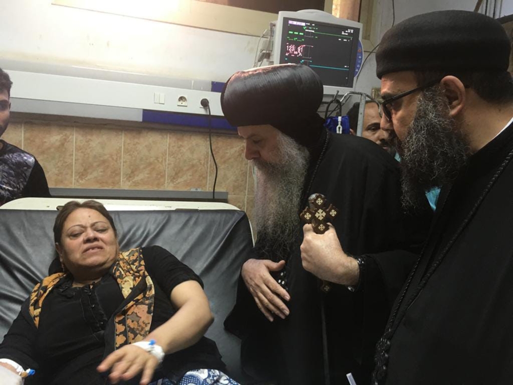 Egypt’s Coptic priest Agathon, center, speaks to a woman, who was wounded after gunmen attacked a bus carrying Coptic Christians, at the Sheikh Fadel hospital in Beni Mazar on Friday. — AFP