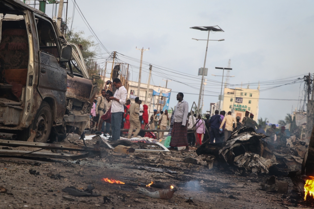 People gather at the scene of twin car bombs that exploded within moments of each other in the Somali capital Mogadishu on Friday. — AFP