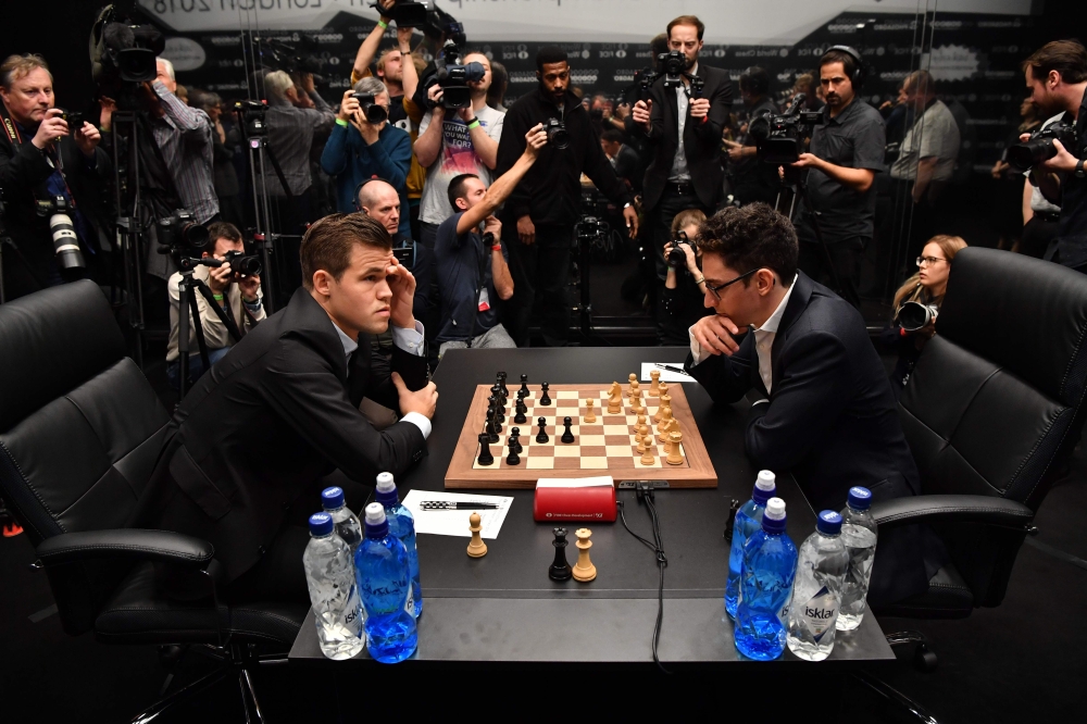 Reigning chess world champion Magnus Carlsen, right, from Norway, plays  Italian-American challenger Fabiano Caruana in the first five minutes of  round three of their World Chess Championship Match in London, Monday, Nov.