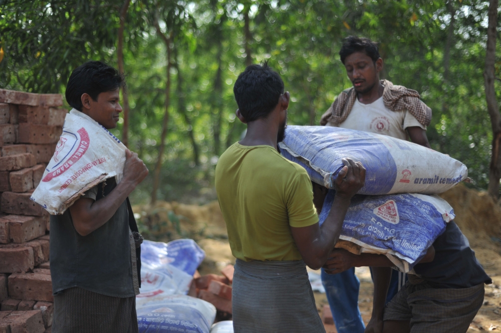 Rohingya construction workers carry bags of cement at an under-construction repatriation center in Ghumdhum near Naikhongchhari in Bangladesh’s Bandarban district on Monday. — AFP
