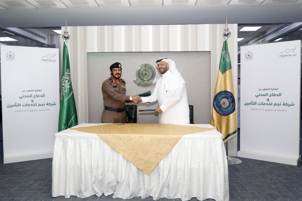 Ibrahim Al Mahboub, Acting CEO of Najm for Insurance Services, and Major General Dr. Hamoud Al Faraj, Assistant General Director of the Civil Defense, sign the agreement