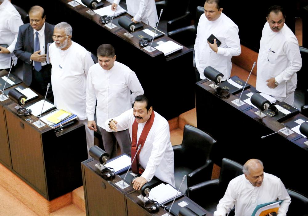 Sri Lanka’s newly appointed Prime Minister Mahinda Rajapaksa makes a joke towards opposition parties seats at the parliament in Colombo on Monday. — Reuters