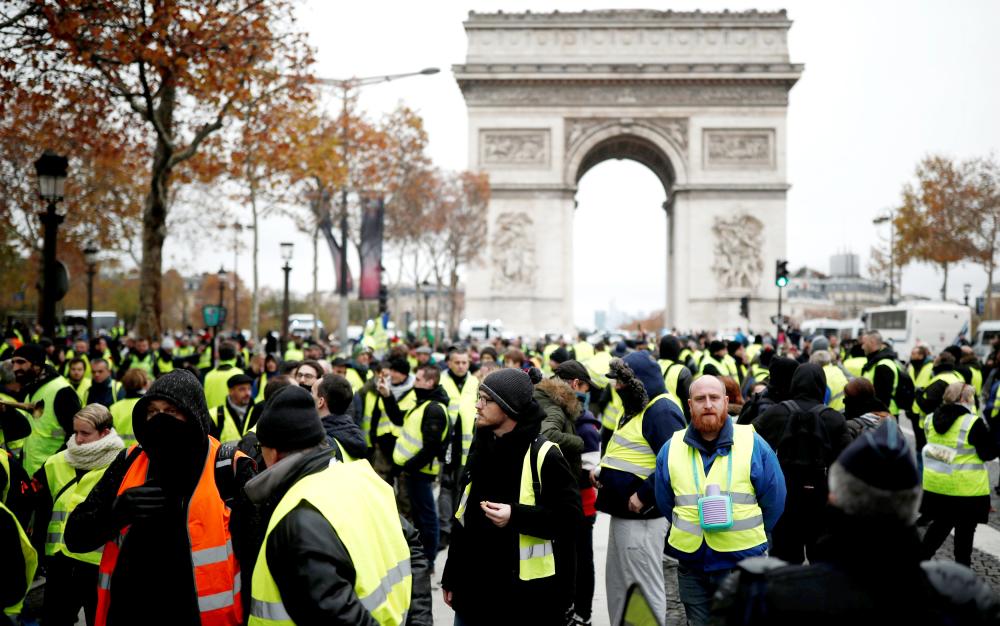 


Protesters wearing yellow vests, a symbol of a French drivers’ protest against higher fuel prices, block the Champs-Elysee in Paris, France, Saturday. — Reuters