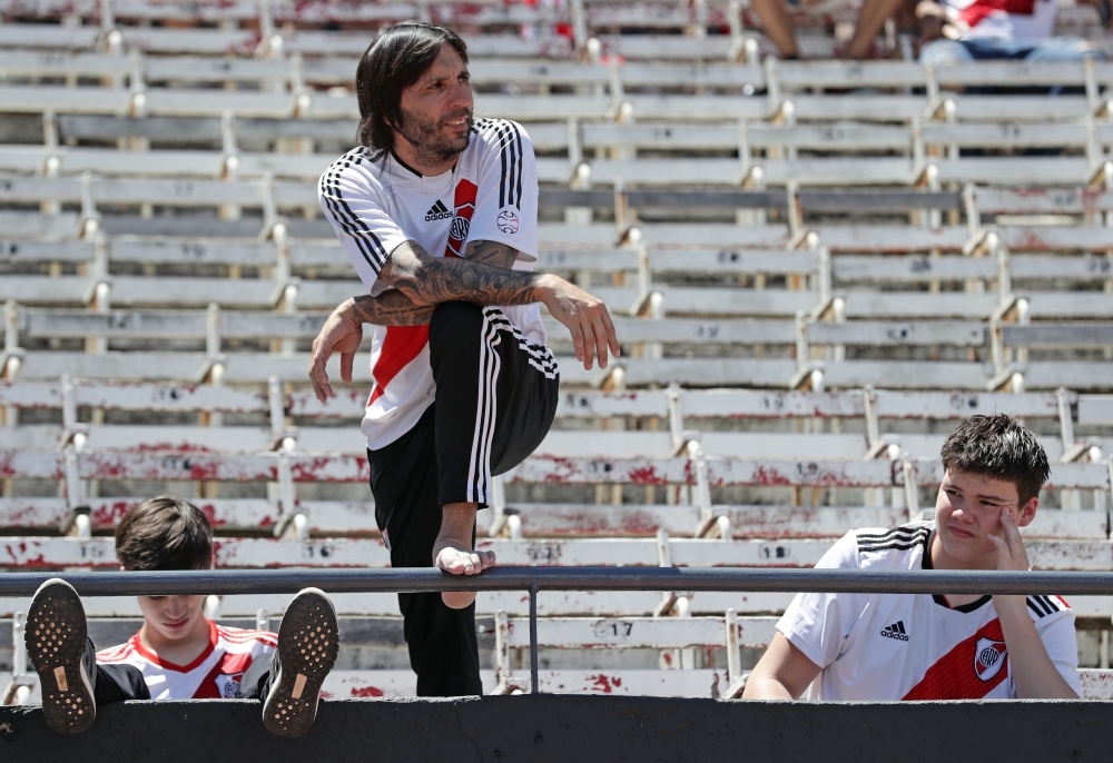 Supporters of River Plate remain in an almost empty stand at the Monumental stadium in Buenos Aires, after the all-Argentine Copa Libertadores second leg final match against Boca Juniors was postponed on Sunday. The second leg of the Copa Libertadores final has been postponed for the second time in as many days following an attack on the Boca Juniors team bus by River Plate fans, Conmebol said Sunday.  — AFP