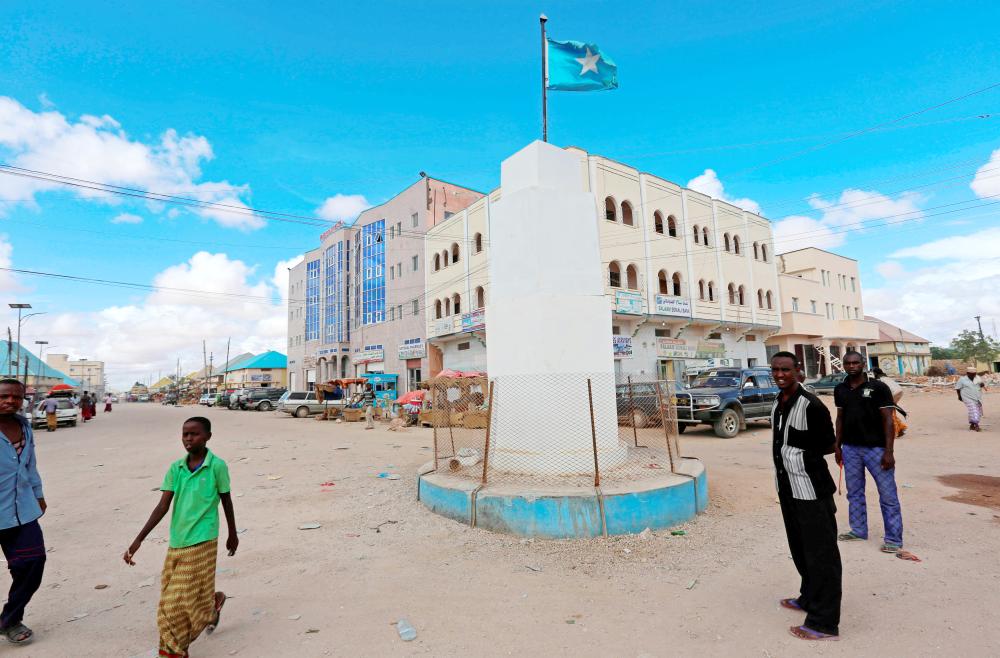 Residents stand near the Somalian national flag at a round-about in Galkayo, a city divided between the semi-autonomous regions of Puntland and Galmudug, in central Somalia in this April 21, 2015 file photo. — Reuters