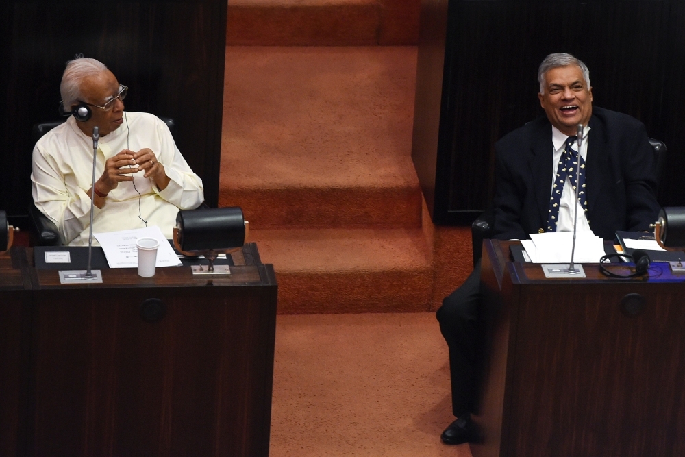 Sri Lanka’s ousted Prime Minister Ranil Wickremesinghe, right, speaks with opposition leader R. Sampanthan, left, in the parliament chamber as members of President Maithripala Sirisena’s party boycott the session in the Sri Lankan parliament in Colombo on Tuesday. — AFP