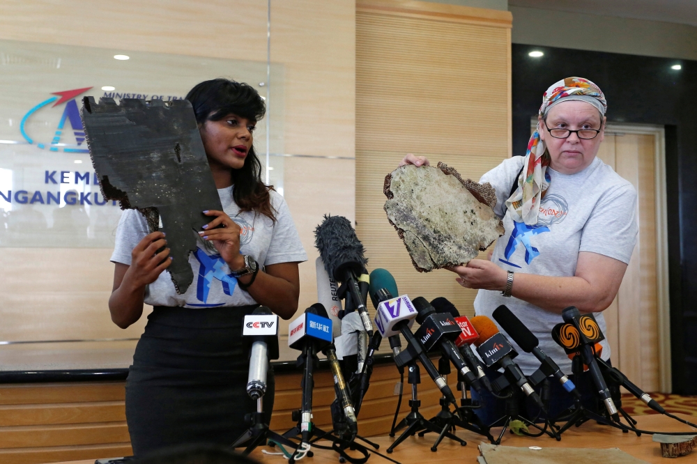 Grace Nathan (L) and Jacquita Gonzales display debris believed to belong to the missing Malaysia Airlines flight MH370 before handing it over to Malaysia's Transport Minister Anthony Loke Siew Fook in Putrajaya, Malaysia on Friday. — Reuters