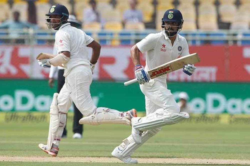 India's Cheteshwar Pujara (L) and skipper Virat Kohli run between the wickets on the third day of the opening cricket Test against Australia in Adelaide Saturday. — Reuters 