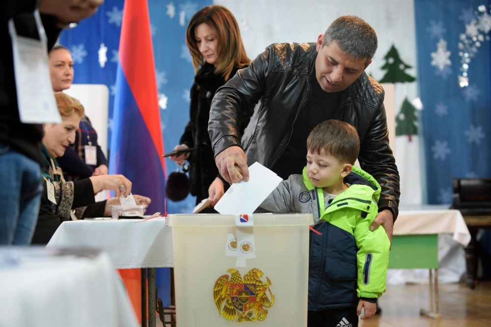 


A man casts his ballot with his son as part of early parliamentary elections in Yerevan, Sunday. — AFP
