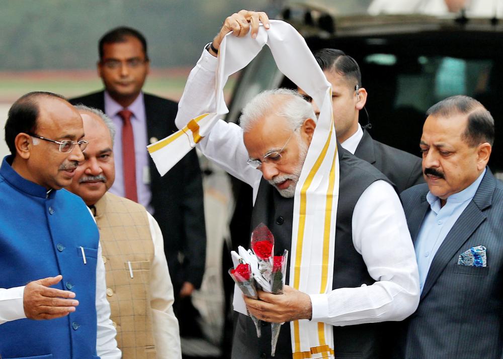 Indian Prime Minister Narendra Modi removes a stole given to him by a minister upon his arrival at the Parliament on the first day of the winter session in New Delhi on Tuesday. — Reuters