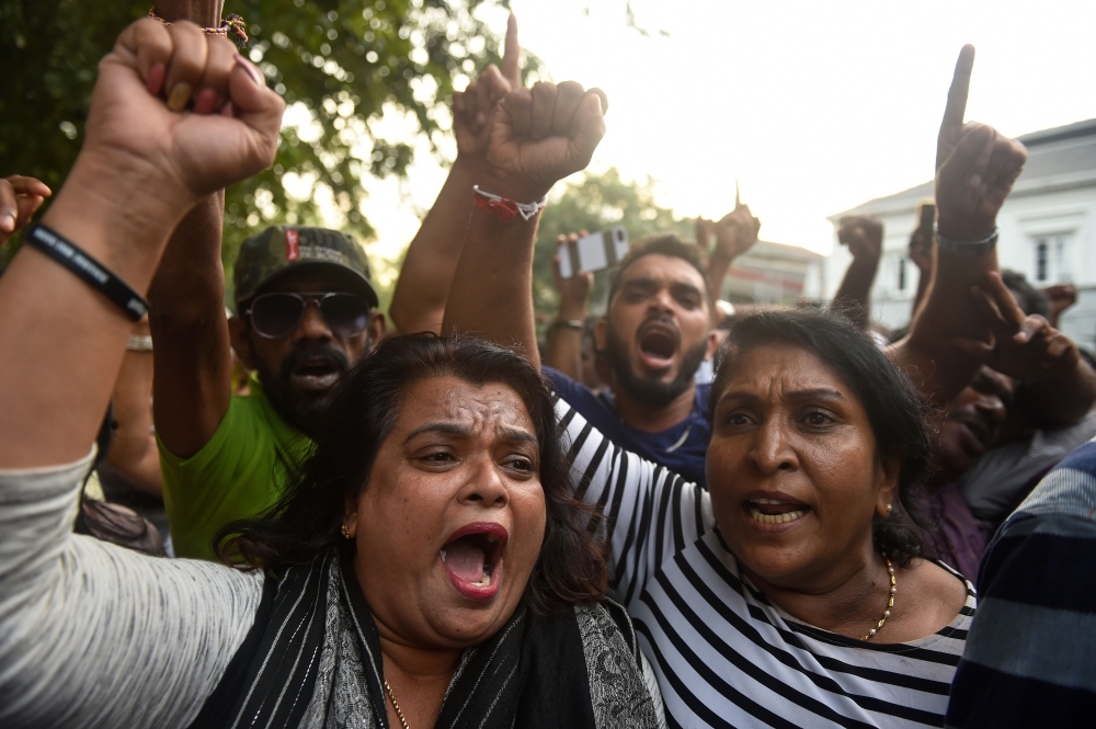 Supporters of ousted Sri Lankan Prime Minister Ranil Wickremesinghe shout slogans as they celebrate the top court’s ruling outside the Sri Lankan Supreme Court in Colombo on Thursday. — AFP