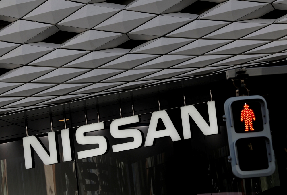 Nissan's signboard is seen behind a traffic sign at its showroom in Tokyo, Japan, on Friday. — Reuters