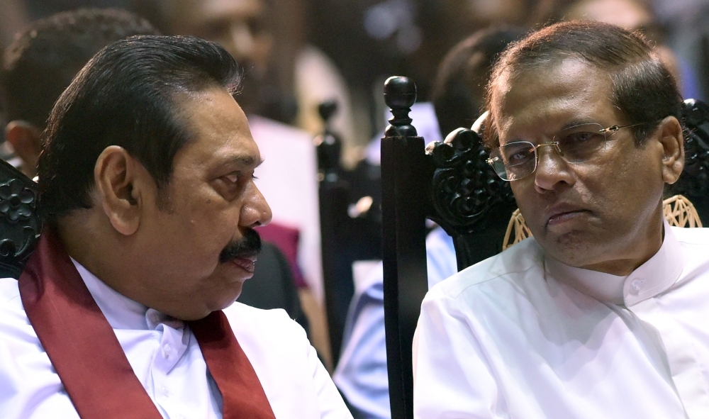 Sri Lankan President Maithripala Sirisena, right, listens to former president and currently-appointed Prime Minister Mahinda Rajapaksa during a ceremony granting employment to social service workers in Colombo in this Nov. 30, 2018 file photo. — AFP