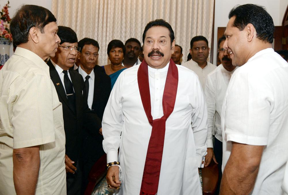 


Sri Lanka’s former leader Mahinda Rajapaksa shares a moment with his political party supporters after he resigned from the prime minister post in Colombo, Saturday. — Reuters