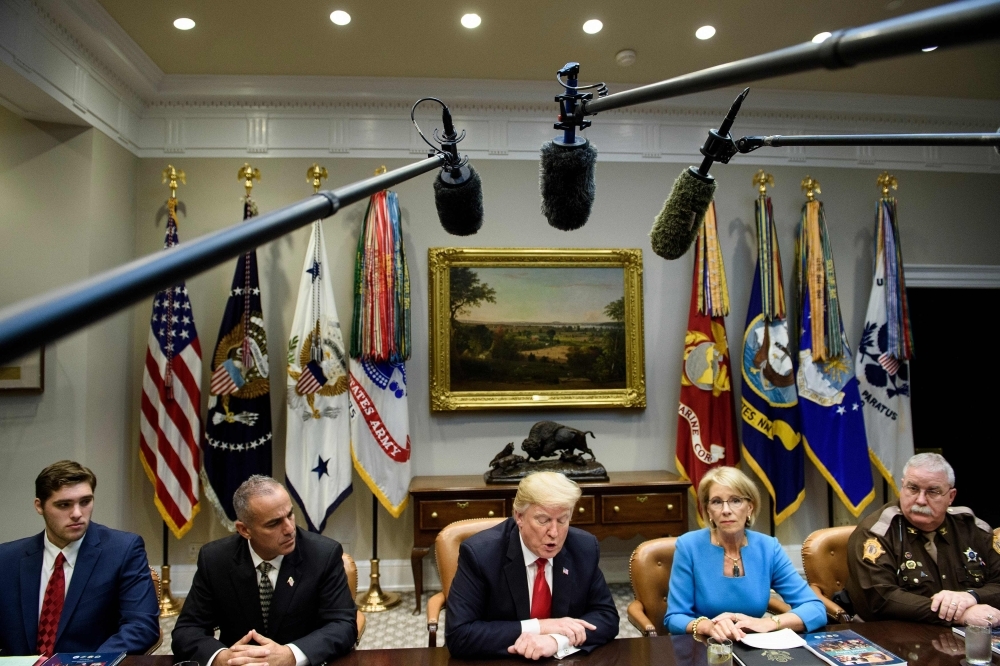 JT Lewis, left, brother of Sandy Hook mass shooting victim Jesse Lewis; Andy Pollack, second left, father of Parkland mass shooting victim Meadow Pollack; US Secretary of Education Betsy DeVos, second right; and Marshall County Kentucky Sheriff Kevin Byars, right, listen while US President Donald Trump speaks during a round-table discussion about school safety in the Roosevelt Room of the the White House in Washington on Tuesday. — AFP