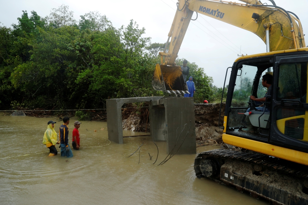 Workers install an emergency bridge over a river, next to a beach hit by tsunami, near Sumur, Banten province, Indonesia, on Wednesday. — Reuters