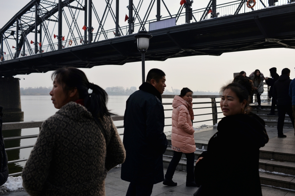 Visitors are seen under the Broken Bridge, adorned with Chinese flags, by the Yalu River separating North Korea and China, in Dandong, Liaoning province, China, in this Dec. 22, 2018 file photo. — Reuters