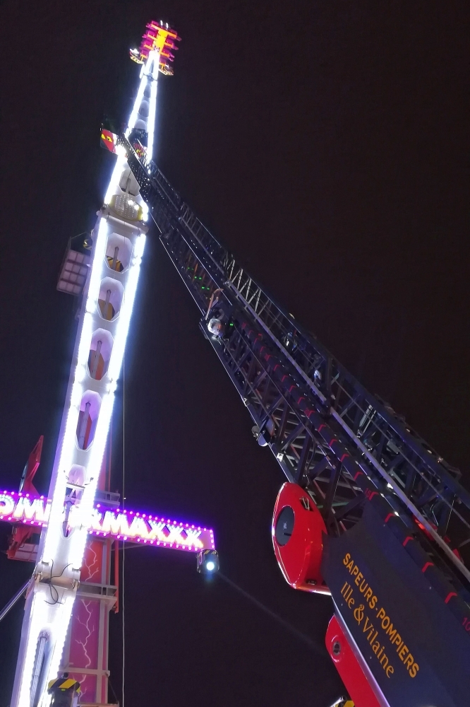 Fire brigade personnel conduct rescue operations after eight people got stuck high in the air on a giant funfair ride in the Brittany city of Rennes late on Monday. — AFP