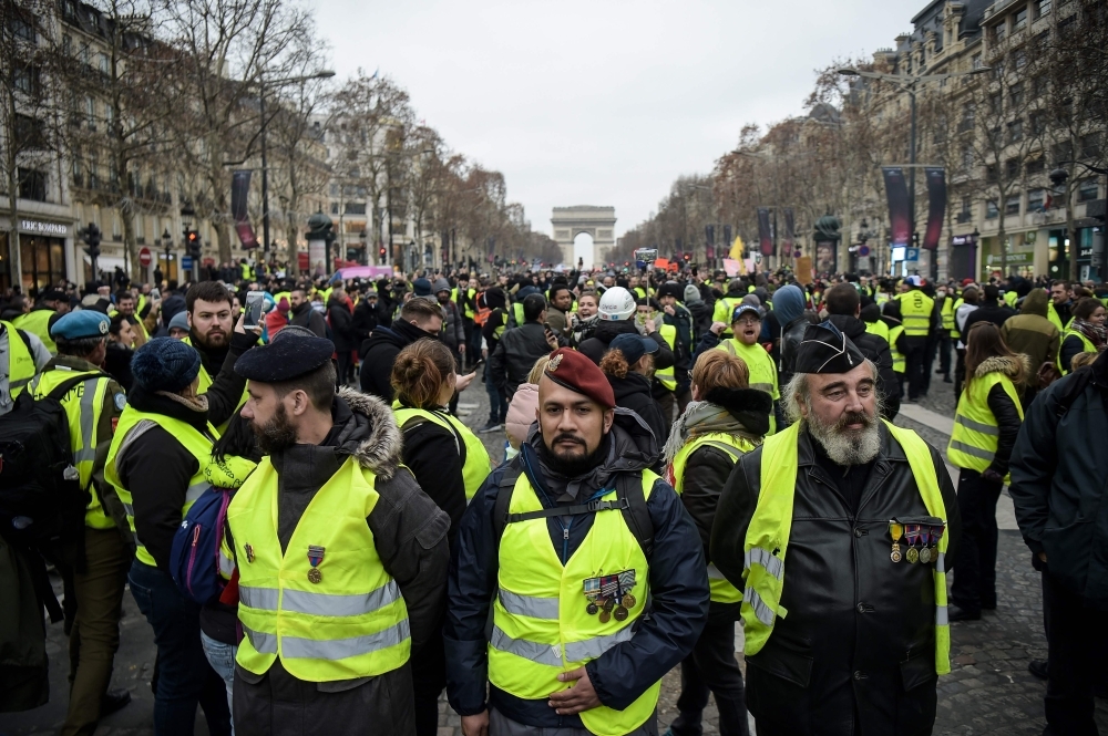 Men wearing campaign medals and yellow vests stand on The Champs-Elysees in Paris on Saturday, during a rally by yellow vest 