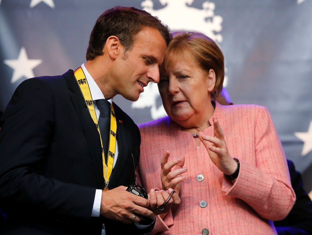 French President Emmanuel Macron speaks with German Chancellor Angela Merkel after being awarded the Charlemagne Prize for “European vision”  in Aachen, Germany, in this May 10, 2018 file photo. — Reuters