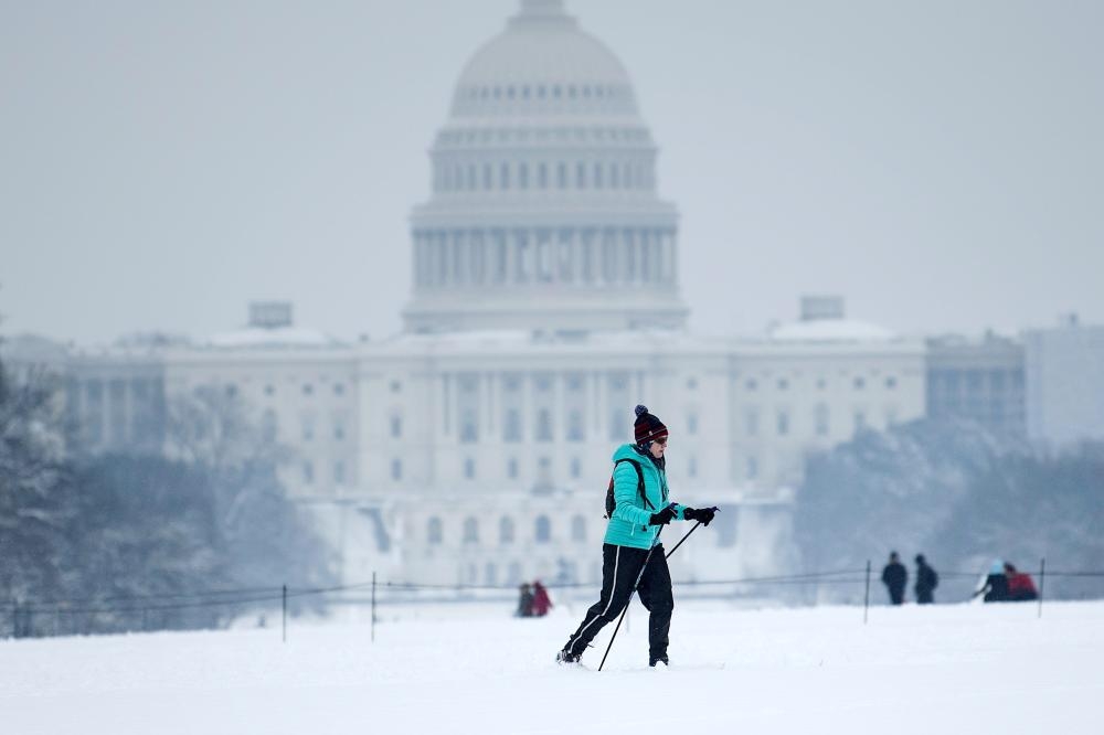 


A cross country skier passes the US Capitol on the National Mall on the 23rd day of a government shutdown during a winter storm in Washington on Sunday. — AFP