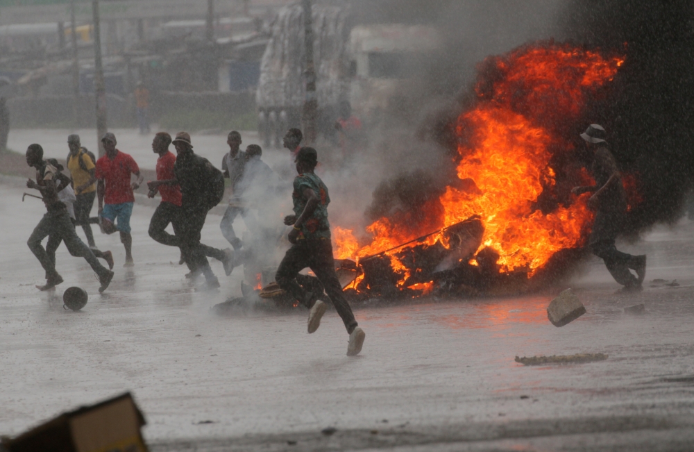People run at a protest as barricades burn during rainfall in Harare, Zimbabwe, on Monday. — Reuters