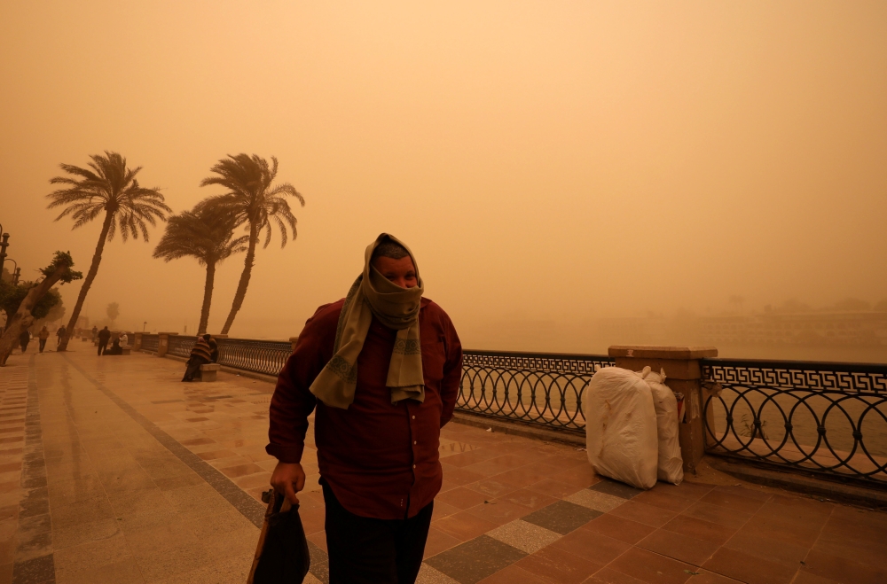 A man covers his face during a sandstorm near the River Nile in Cairo on Wednesday. — Reuters