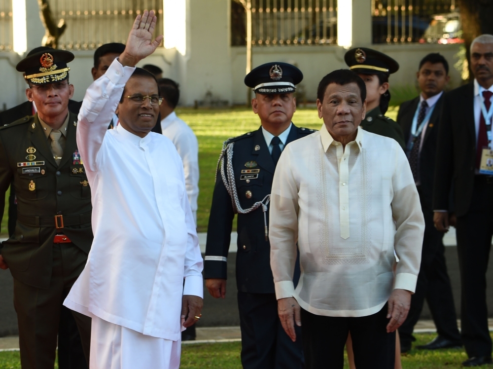Sri Lankan President Maithripala Sirisena, left, waves to members of the media as Philippine President Rodrigo Duterte, right, looks on after reviewing an honor guard during a welcoming ceremony at the Malacanang Palace grounds in Manila on Wednesday. — AFP