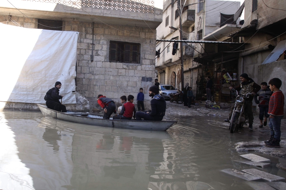 A man ferrying children and delivering bread paddles a small boat along a flooded street in the town of Darkush, in the west of Idlib province, Syria, on Thursday, following heavy rains that saw the Orontes River (Assi River) break its banks and flood parts of the town and the nearby orchards.  — AFP