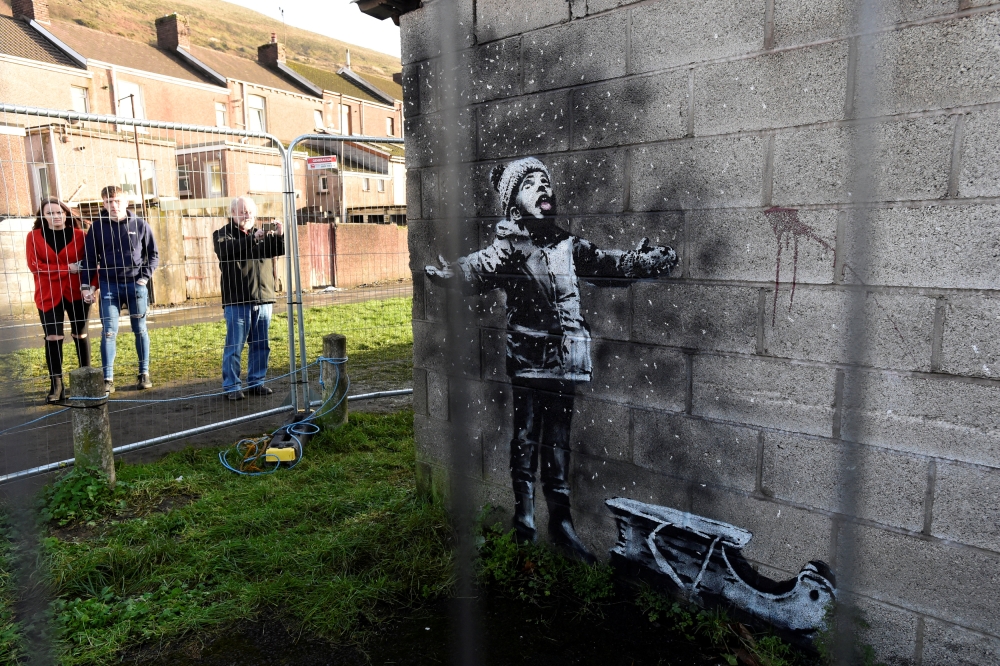 People view new work by the artist Banksy that appeared during the week on the walls of a garage in Port Talbot, Britain. — Reuters